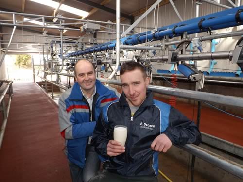 Christy Pender, the local DeLaval dealer with young dairy farmer Robert English drinking a toast to his new milking parlou